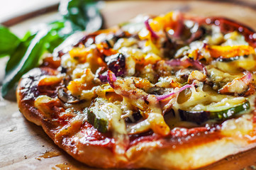 vegetarian pizza with Mozzarella cheese, grilled zucchini, mushrooms, red onion, pepper and fresh basil. Italian pizza on wooden table background