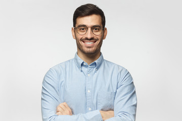 Portrait of young male teacher smiling, wearing blue shirt, isolated on gray background - obrazy, fototapety, plakaty