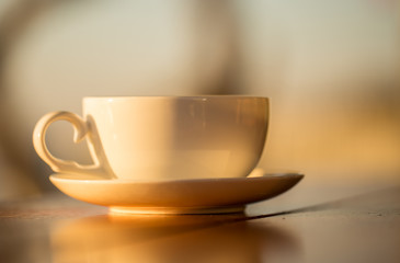 coffee cup with sunset background on wood table.