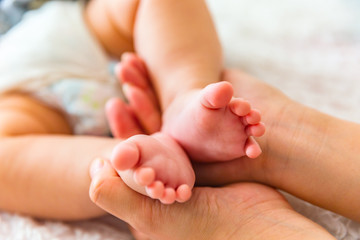 Obraz na płótnie Canvas Mother holding the baby's feet