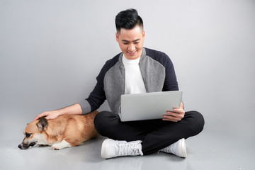 Handsome young businessman is using laptop while sitting with his dog on floor