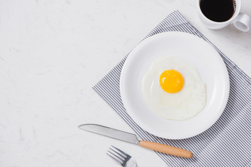 Top view of white dish with fried egg on white background.