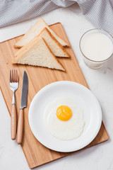 Fried eggs with toasts and milk on the table