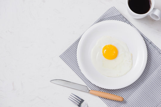 Top View Of White Dish With Fried Egg On White Background.