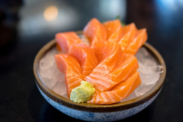 Salmon sashimi with vegetable and ice in a bowl, served in a restaurant