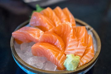 Salmon sashimi with vegetable and ice in a bowl, served in a restaurant