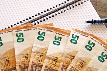 Finanzas, cuentas y economía. Billetes de 50€, cuaderno y bolígrafo.
