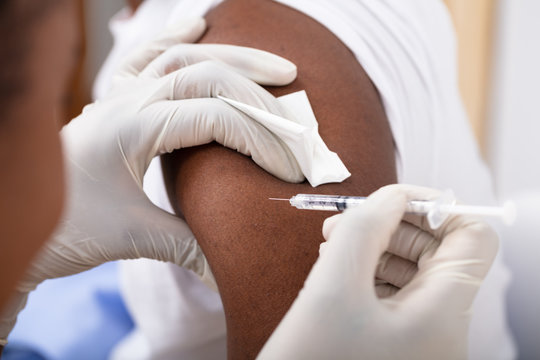 Doctor Injecting Syringe To Patient's Arm - Powered by Adobe