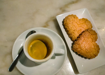 Heart cookies with cup of coffee top view in a real coffee shop. Suitable for valentine's day, couple romance, weddings, and love concepts. Copy space available