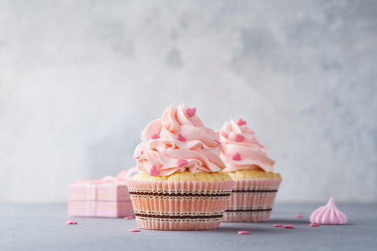 Pink cupcakes, gift box and candy. Creative dessert background.