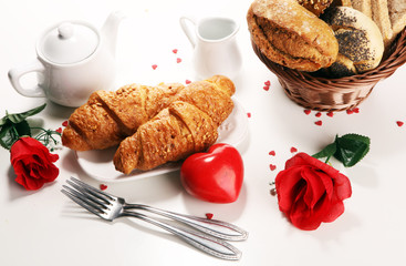 breakfast on table with bread buns, croissants, coffe and juice on valentines day.