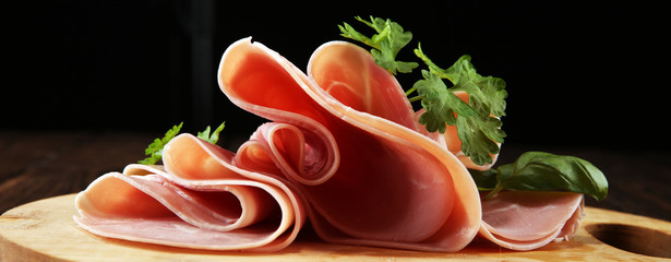Sliced ham with parsley on table. Fresh prosciutto. Pork ham sliced.