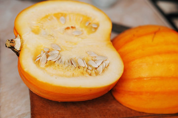 Yellow pumpkin is cut in the kitchen on a wooden board. The woman is going to cook porridge with pumpkin at home