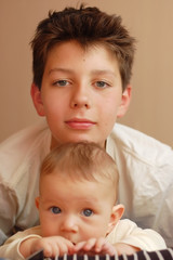 A young boy plays with his younger brother, hugs him and speaks to him good words