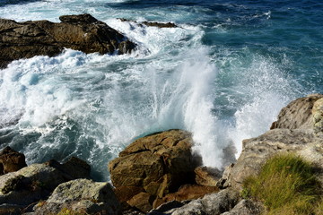 Wild waves splashing against the rocks. Blue sea with white foam, Galicia, Spain.