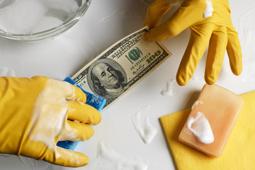 Laundering of money. A man in gloves washes a hundred dollars. - 244167153