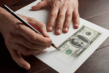 A man draws a hundred dollars bill on paper. - 244167189