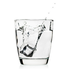 Ice cubes splashing into glass of whiskey isolated on white. brandy in glass with ice. alcohol. liqueur glass