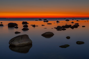 Sunset seascape with boulders on the shore of Baltic sea. Amazingly colorful sky.
