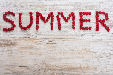 Inscription Summer made of raspberry berries on a textured light wooden background. Flat top view, place for text. Flat lay, Copy space.