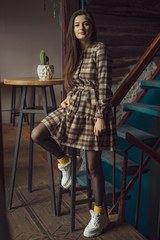 French wear style. How wear checkered dress like fashion girl. Girl, woman with long black hair posing in old cafe background. Fashionable brunette female.