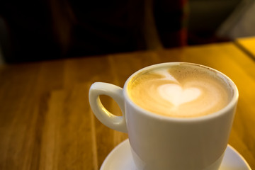 Cappuccino coffee with heart shaped crema in a white cup