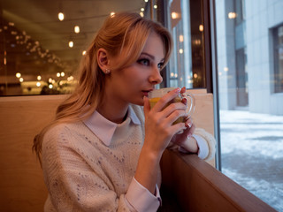 Beautiful young woman in a cozy cafe with a cup of tea
