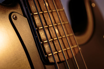 Horizontal detail of the fret board of a bass guitar, on a dark background