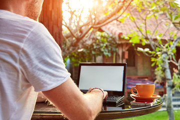 Man with coffee / tea and laptop on a home porch.
