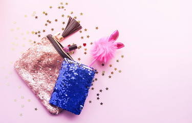 Bright composition of fashion accessories. Glitter sequins purse, notepad, funny pen and decorative tinsel. Different objects on soft pastel background. Flat lay, top view