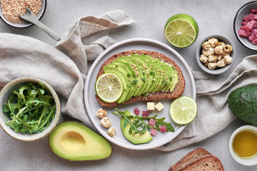 Green salad and avocado sandwich, top view on grey stone background