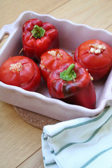 Baked red peppers and tomatoes stuffed with rice on wooden table