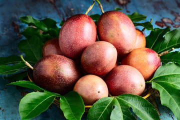 Fresh passion fruit with original leaves on blue wooden background