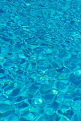 Fototapeta na wymiar Blue water in swimming pool background. Ripple Water in swimming pool with sun reflection. Blue swimming pool rippled water detail. vertical photo.