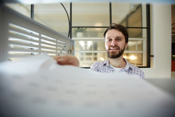 Fototapeta premium Young accountant or manager taking out financial papers from safe while working in office