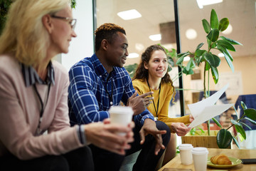 Young successful economists gathered by table in office for brainstorming and discussing new ideas