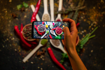 Hands taking photo colourful various herbs and spices with smartphone