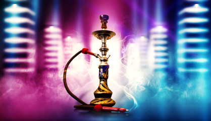 Hookah smoking on the background of an empty dark room, a corridor with neon glowing piles. Spotlight, laser beams, smoke.