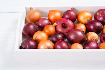 onions on white wood tray, wooden table background