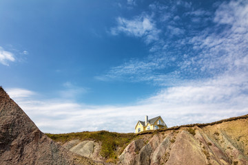 Yellow house on clifftop, Magdalen Islands, Canada. Image taken from a public position.