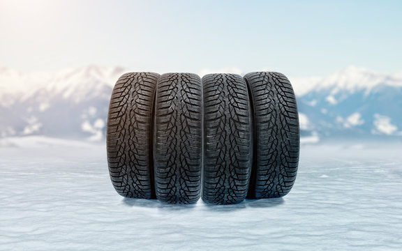 Four car winter tires on an icy surface as a symbol of safe driving during snowy season