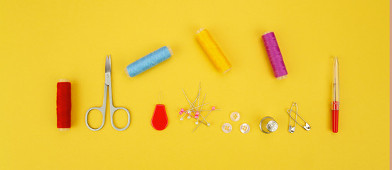 Multiple accessories for sewing view from above on a yellow background.