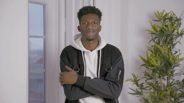 Portrait of smiling young man standing indoors. African American man posing with folded arms. Young man concept