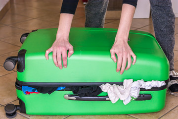 Frau versucht überfüllten Koffer zu schließen
