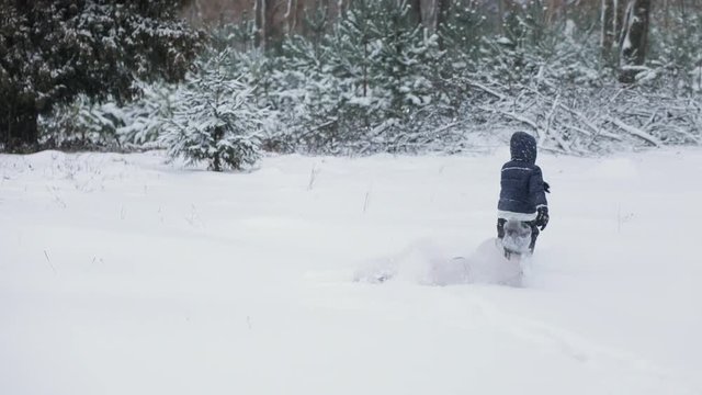 Slow motion view of two funny kids having fun in snowy winter park, girl falls down the ground while trying cath little boy, carefree childhood concept