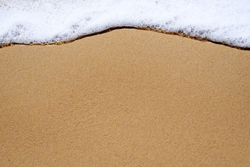 Fototapeta na wymiar Sea wave cools down on the sandy beach, background