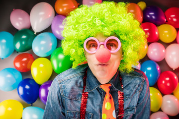 Obraz na płótnie Canvas Mann in Karnevalsstimmung auf buntem Hintergrund aus Lüftballons.party Konzept