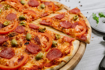 Delicious pizza Neapolitana with tomato sauce, mozzarella and ham on the white wooden background