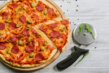 Delicious pizza Neapolitana with tomato sauce, mozzarella and ham on the white wooden background