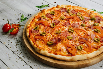 Tasty pizza Chachatore with mozzarella, salami and olives on the white wooden background